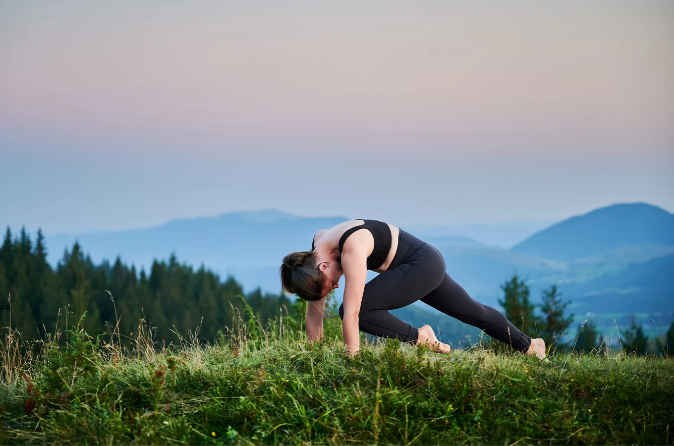 a woman doing yoga outdoors in the mountains