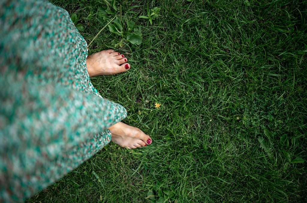 a woman stands barefoot on grass